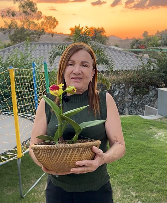 Rosângela com uma Cattleya no cesto, ao pôr do sol